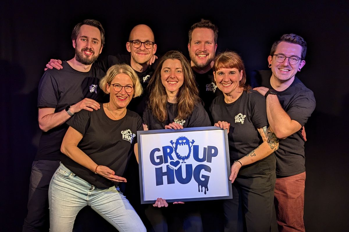 Das Group-Hug-Ensemble mit dem Group-Hug-Logo auf der Bühne